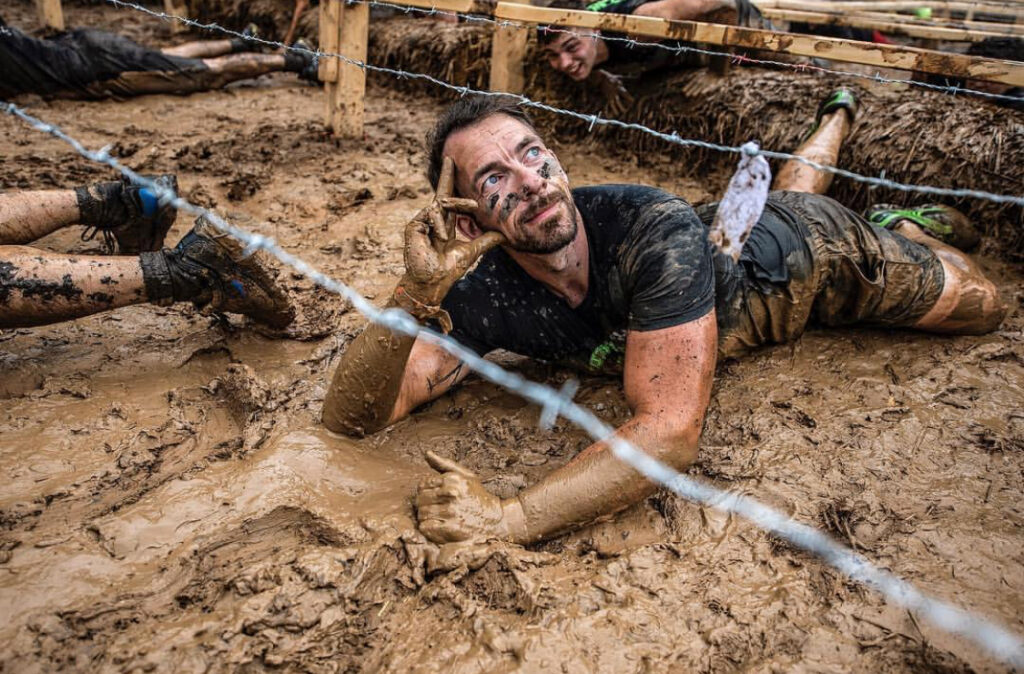 Mann liegt mit nachdenklicher Pose im Matsch